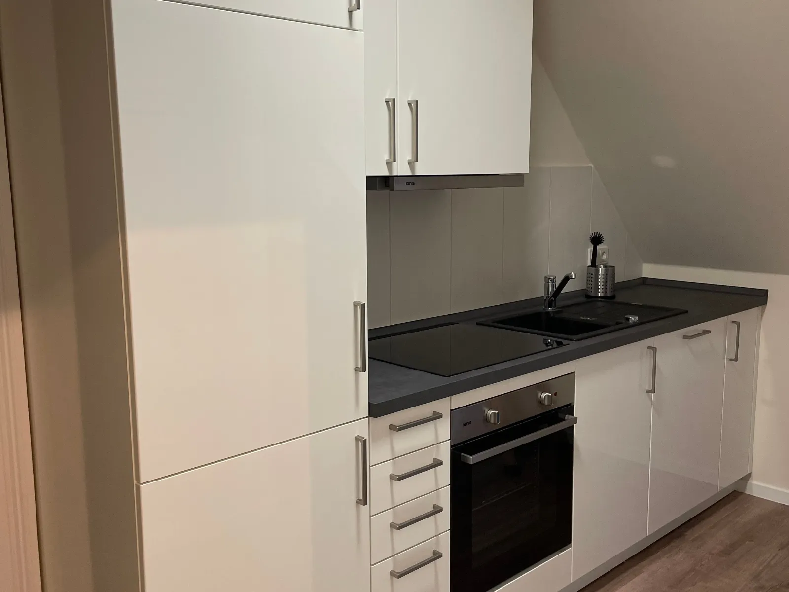 Eine kleine Küche mit Herd, Waschbecken, Kühlschrank und Backofen.